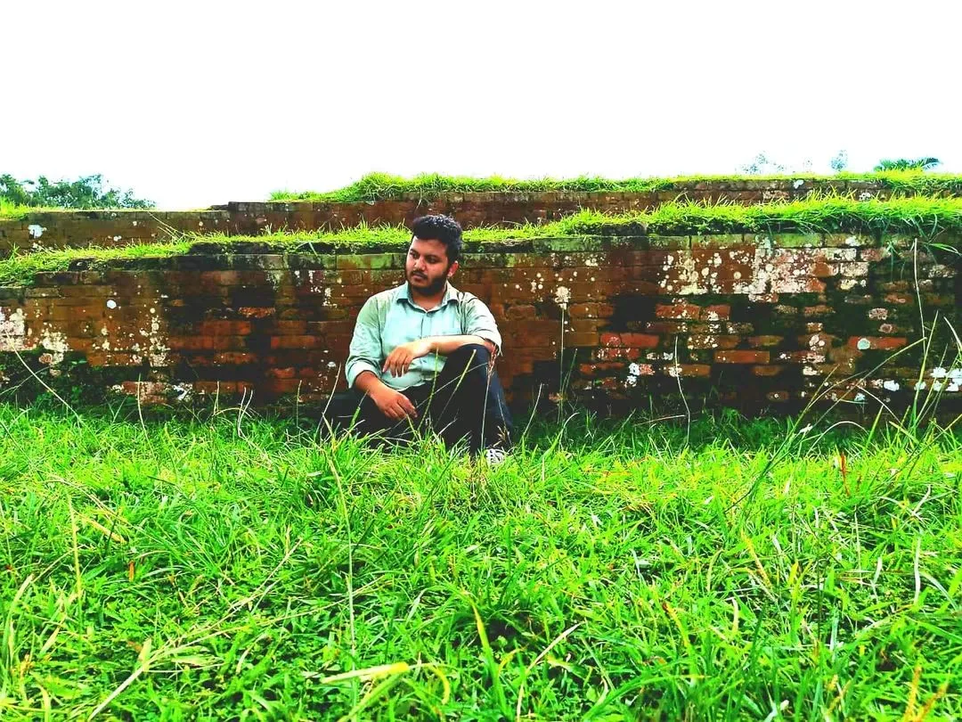 Asif Rezan seated in a green natural landscape in Bangladesh